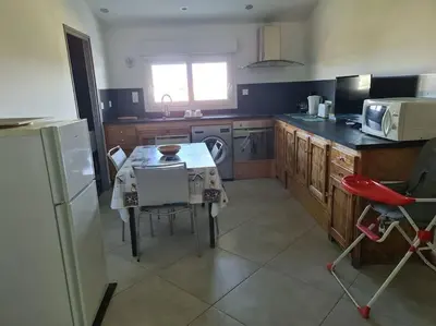 a kitchen with a table and a stove and a refrigerator at Appartement de détente et vue sur montagnes in Ghisonaccia