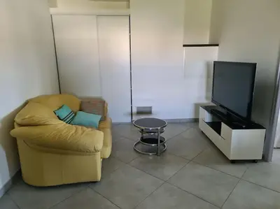 a living room with a chair and a tv at Appartement de détente et vue sur montagnes in Ghisonaccia