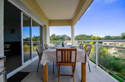 a dining room with a table and chairs on a balcony at Casamea - Vue mer, Terrasse, Clim, Proche Plage in Porticcio