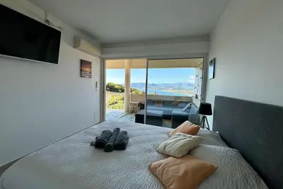 a bedroom with a bed with two pairs of slippers on it at Casamea - Vue mer, Terrasse, Clim, Proche Plage in Porticcio