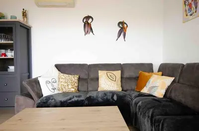 a living room with a couch with pillows and a table at Casamea - Vue mer, Terrasse, Clim, Proche Plage in Porticcio