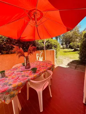 a table with a red umbrella on a patio at Appartement front de mer et piscines in Ghisonaccia