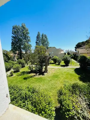 a yard with green grass and trees and a house at Appartement front de mer et piscines in Ghisonaccia