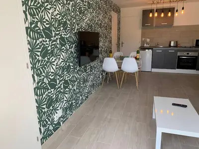 a kitchen with white chairs and a green and white wall at bellucciu di porto vecchio***. (Piscine chauffée) in Porto-Vecchio