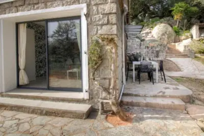 a stone house with a glass door and a table at bellucciu di porto vecchio***. (Piscine chauffée) in Porto-Vecchio