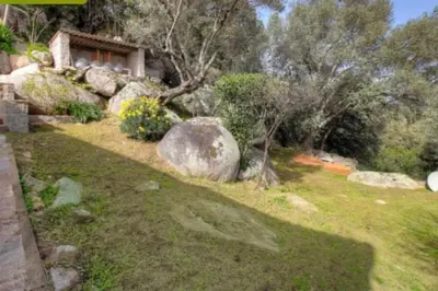 a garden with rocks and trees and a house at bellucciu di porto vecchio***. (Piscine chauffée) in Porto-Vecchio