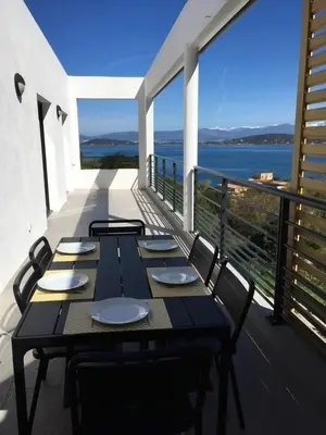 a table on a balcony with a view of the water at Les Terrasses de la Pinède - Appt climatisé in Coti-Chiavari