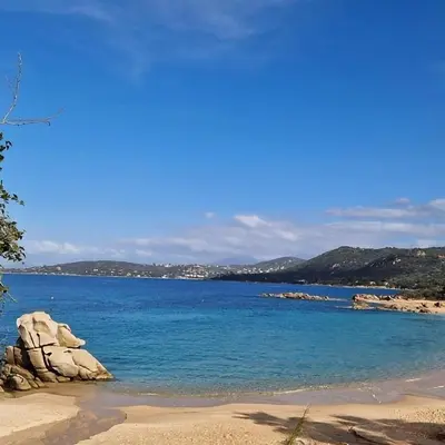 a beach with blue water and mountains in the background at Les Terrasses de la Pinède - Appt climatisé in Coti-Chiavari