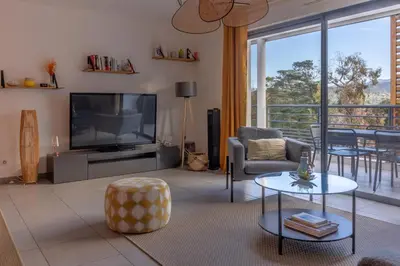 a living room with a television and a table and chairs at Les Terrasses de la Pinède - Appt climatisé in Coti-Chiavari