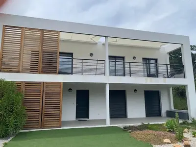 a house with wooden shutters and a balcony at Les Terrasses de la Pinède - Appt climatisé in Coti-Chiavari