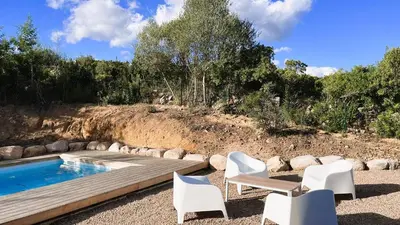 a swimming pool with two white chairs and a wooden deck at Villa Copains, 5 pers, piscine chauffée, 5 mn plage in Cirendinu