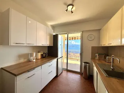a kitchen with white cabinets and a view of the ocean at Appartement L'Aiglon 1 centre-ville Ajaccio in Ajaccio