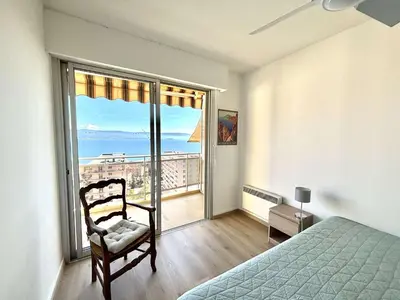 a bedroom with a bed and a chair and a large window at Appartement L'Aiglon 1 centre-ville Ajaccio in Ajaccio