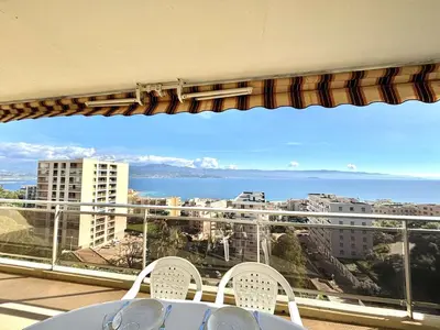 a balcony with a table and chairs and a view of the ocean at Appartement L'Aiglon 1 centre-ville Ajaccio in Ajaccio