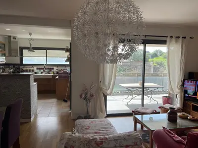 a living room with a chandelier and a table and a kitchen at APPARTEMENT STANDING AJACCIO 5mn A PIEDS PLAGE DU RICANTO AJACCIO in Ajaccio