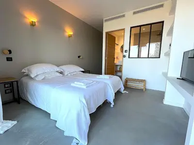 a bedroom with a white bed and a television at Villa San Joseph in Cargèse