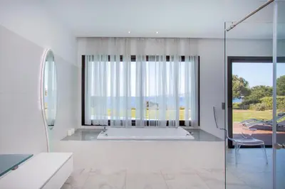 a white bathroom with a tub and a large window at Villa HAPPY DAYS in Pietrosella
