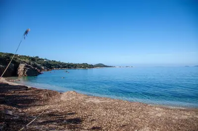a beach with blue water and a rocky shore at Villa HAPPY DAYS in Pietrosella