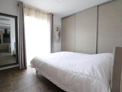 a bedroom with a large white bed and a mirror at La Maison de vacances à Ajaccio- Proche plage et aéroport- Extérieur privatif avec barbecue in Ajaccio