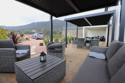 a patio with wicker chairs and a table and a car at La Maison de vacances à Ajaccio- Proche plage et aéroport- Extérieur privatif avec barbecue in Ajaccio