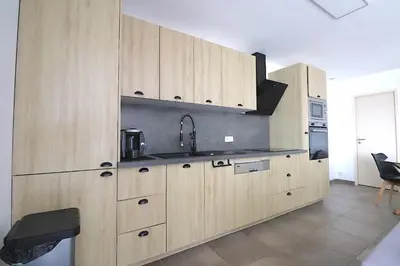 a kitchen with wooden cabinets and a sink at La Maison de vacances à Ajaccio- Proche plage et aéroport- Extérieur privatif avec barbecue in Ajaccio