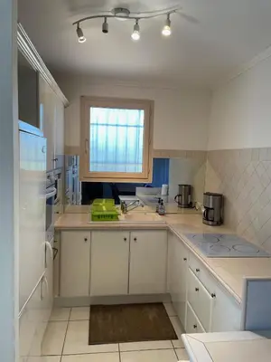 a kitchen with white cabinets and a sink and a window at Villa Bell'am Corse in Porto-Vecchio