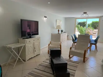 a living room with a flat screen tv and chairs at Villa Bell'am Corse in Porto-Vecchio
