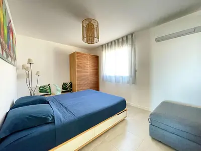 a bedroom with a blue bed and a window at Appartamentu A Leccia in Grosseto-Prugna