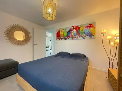 a bedroom with a blue bed and a painting of parrots at Appartamentu A Leccia in Grosseto-Prugna