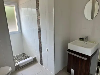 a white bathroom with a shower and a sink at Grand appartement T4 - piscine - vue féérique in Propriano