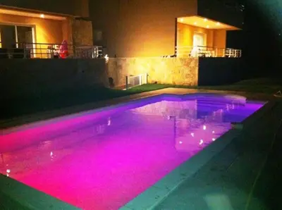 a swimming pool with pink lighting in a house at Grand appartement T4 - piscine - vue féérique in Propriano