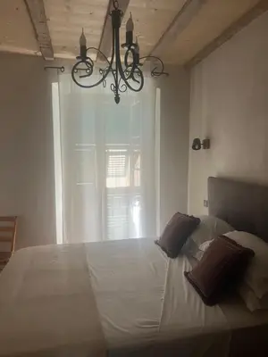 a bedroom with a large white bed with a chandelier at Appartement prestige, cour Paoli in Corte