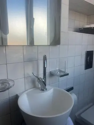 a white sink in a white tiled bathroom at Appartement prestige, cour Paoli in Corte