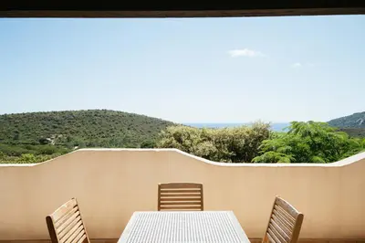 a table and chairs on a balcony with a view at Les Hauts de Santa Giulia in Porto-Vecchio