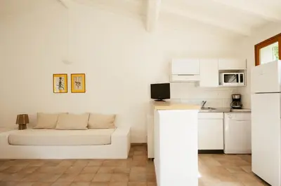 a white room with a bed and a kitchen at Les Hauts de Santa Giulia in Porto-Vecchio