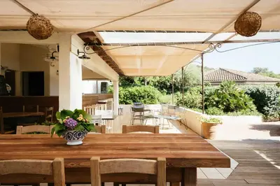 a wooden table with a vase of flowers on a patio at Les Hauts de Santa Giulia in Porto-Vecchio
