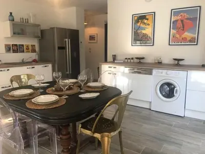 a kitchen with a table with chairs and a washing machine at LES VILLAS LECCI E MARE in Zonza