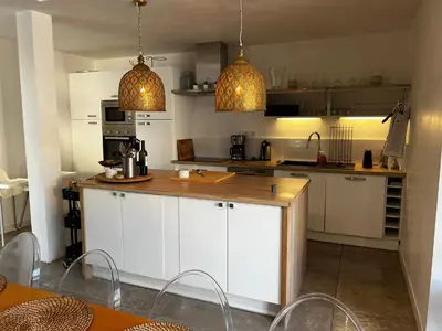 a kitchen with white cabinets and two pendant lights at LES VILLAS LECCI E MARE in Zonza