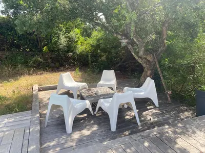 three white chairs and a table on a deck at LES VILLAS LECCI E MARE in Zonza