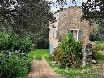 an old stone house with a dirt road in front of it at MAISON DE CARACTERE AVEC PISCINE in Sartène