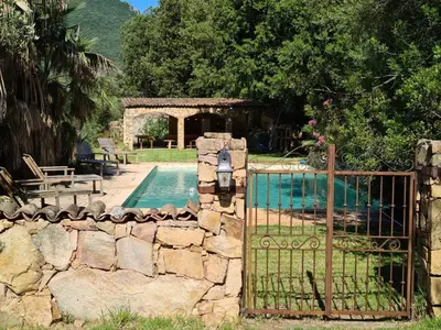 a gate to a swimming pool with a stone fence at MAISON DE CARACTERE AVEC PISCINE in Sartène