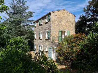 a stone house with a balcony on the side of it at MAISON DE CARACTERE AVEC PISCINE in Sartène