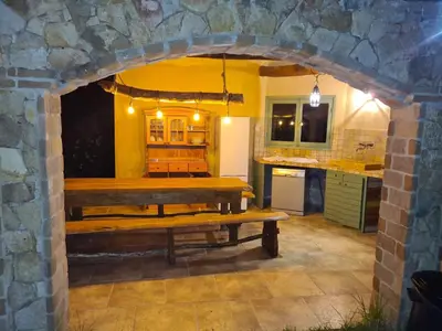 a kitchen with a wooden table in a stone archway at MAISON DE CARACTERE AVEC PISCINE in Sartène