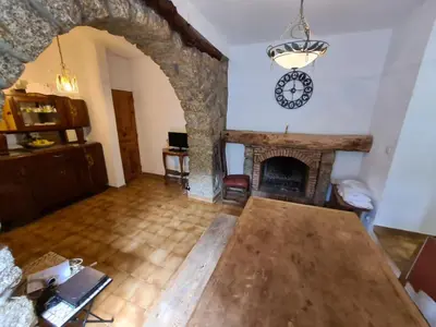 a living room with a fireplace and a clock on the wall at MAISON DE CARACTERE AVEC PISCINE in Sartène