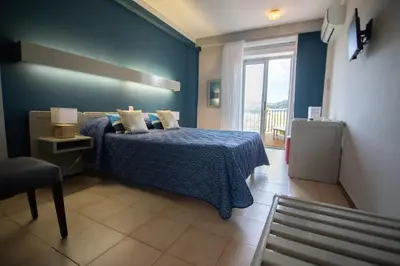 a blue bedroom with a bed and a window at Hôtel Beach in Propriano
