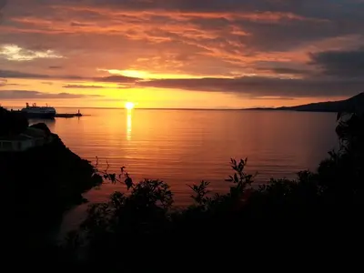 a sunset over a body of water with a boat at Hôtel Beach in Propriano