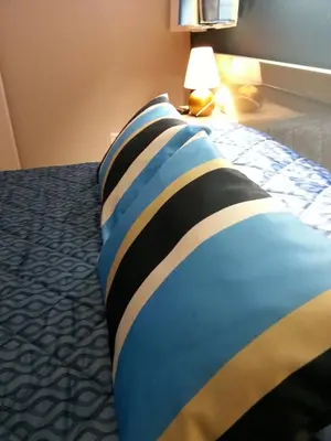 a bed with a colorful pillow on top of it at Hôtel Beach in Propriano