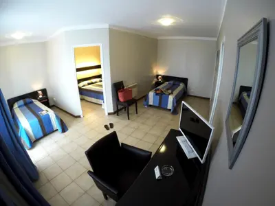 a room with two beds and a desk with a computer at Hôtel Beach in Propriano