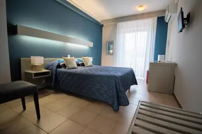 a blue bedroom with a bed and a window at Hôtel Beach in Propriano