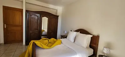 a bedroom with a bed with a yellow blanket on it at T2 Paisible Quartier Vigna Majo, Olmeto in Olmeto